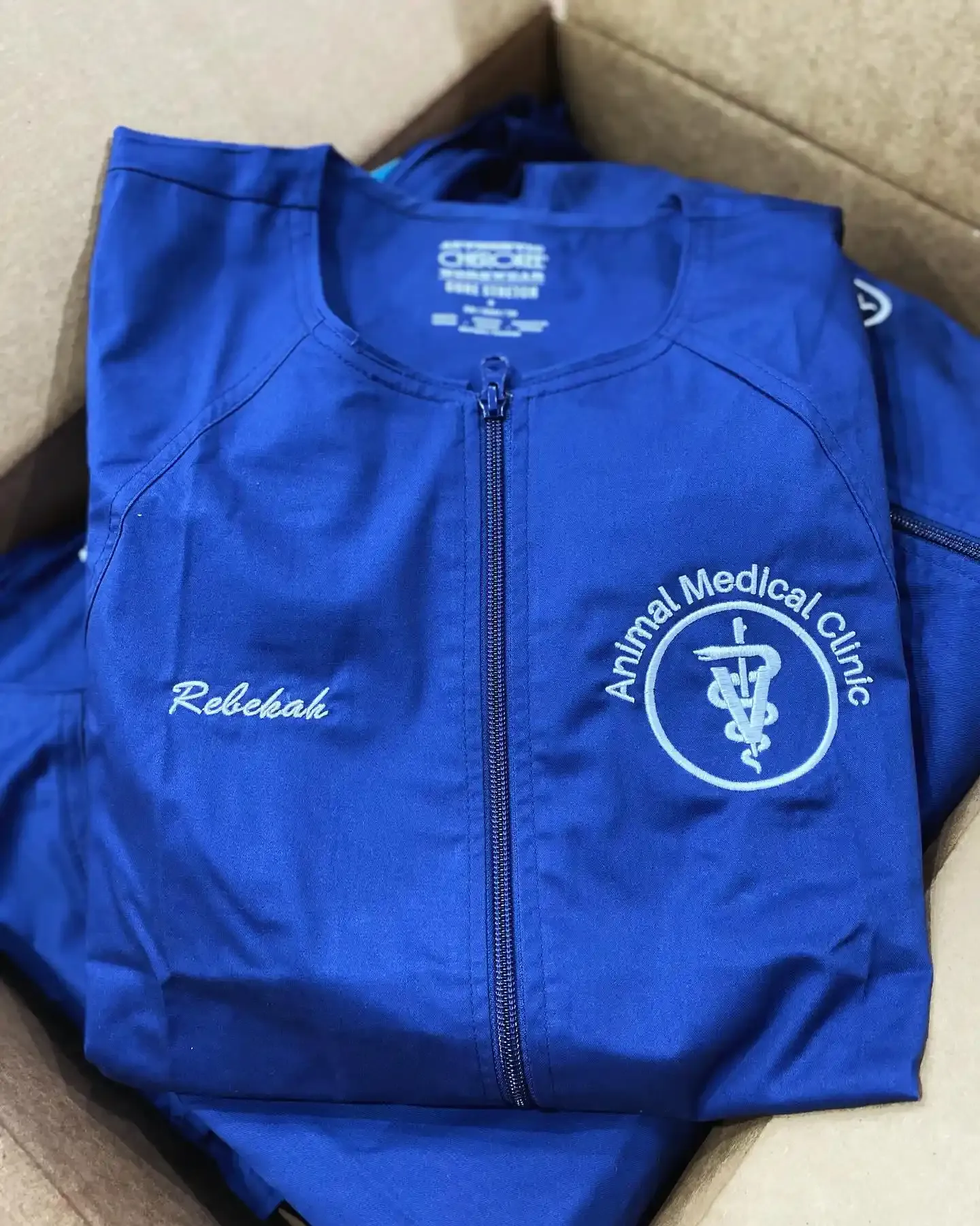 Custom digitized logo for Animal Medical Clinic and personalized name embroidery on blue medical scrubs by Sassy Digitizing.